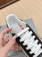 Prada unisex sneakers close-up: white collar and toe, black patent upper, white laces