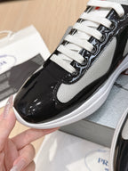 Prada unisex sneakers close-up: white laces over black patent leather upper and white sole