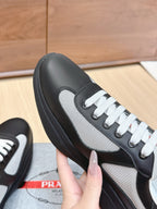 Prada unisex sneaker close-up: black leather and grey mesh side with white laces