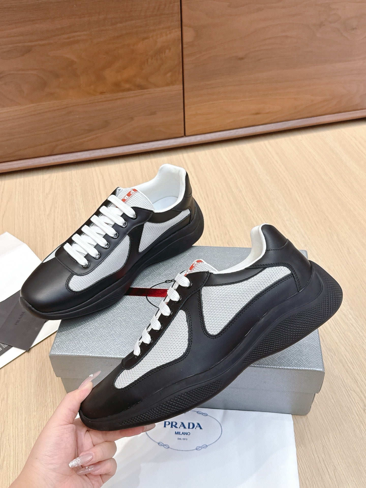 Prada unisex sneakers with black uppers and white swoosh, lace-up side view