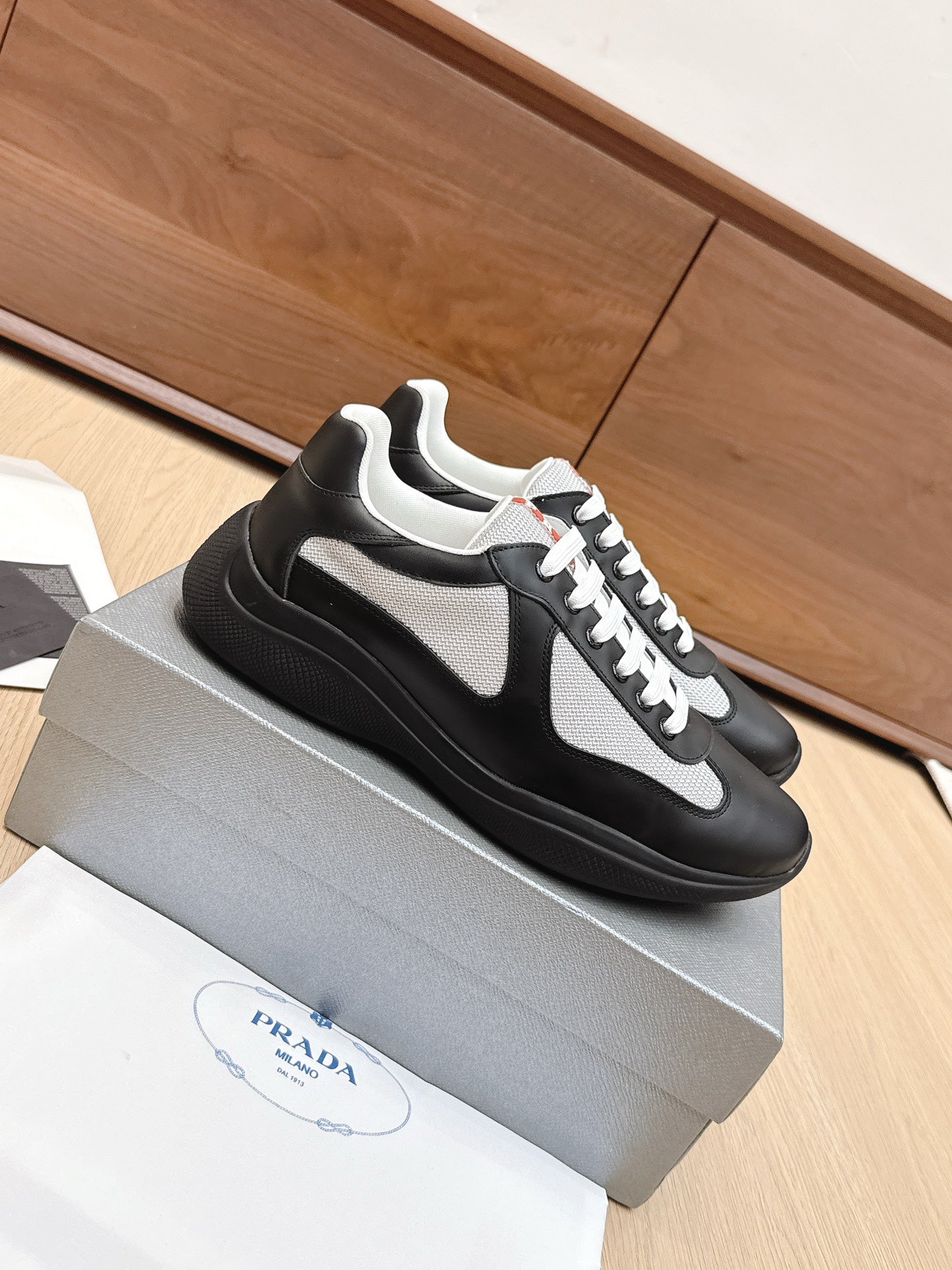 Prada unisex sneakers, black with white swoosh, white laces, and thick sole
