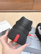 Prada unisex sneaker heel close-up, black leather with red logo patch and textured sole
