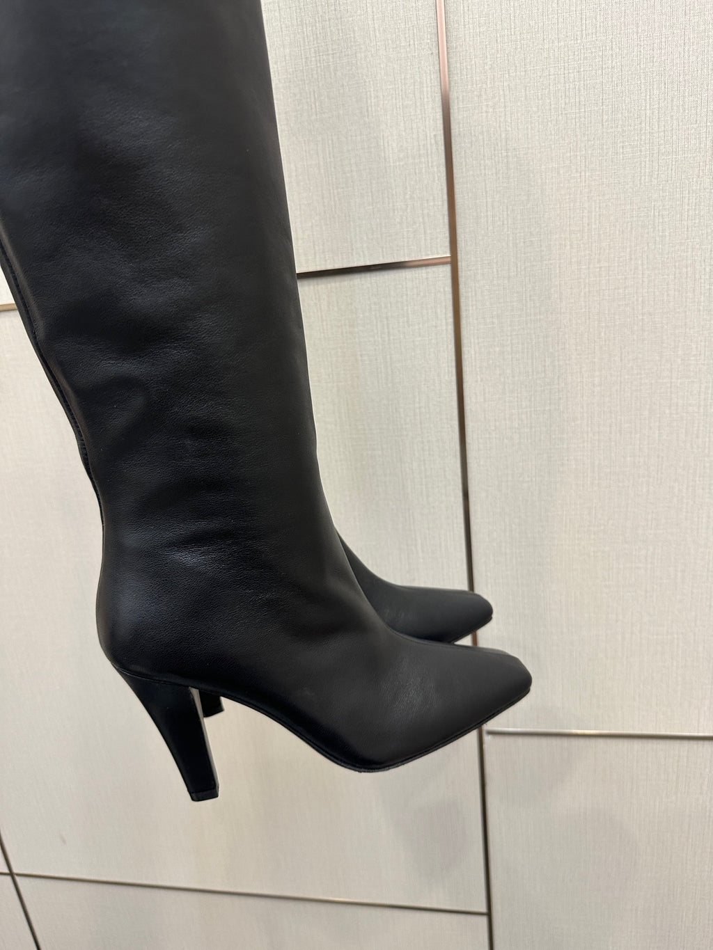 Black knee-high boot with pointed toe and stiletto heel, smooth leather-look upper
