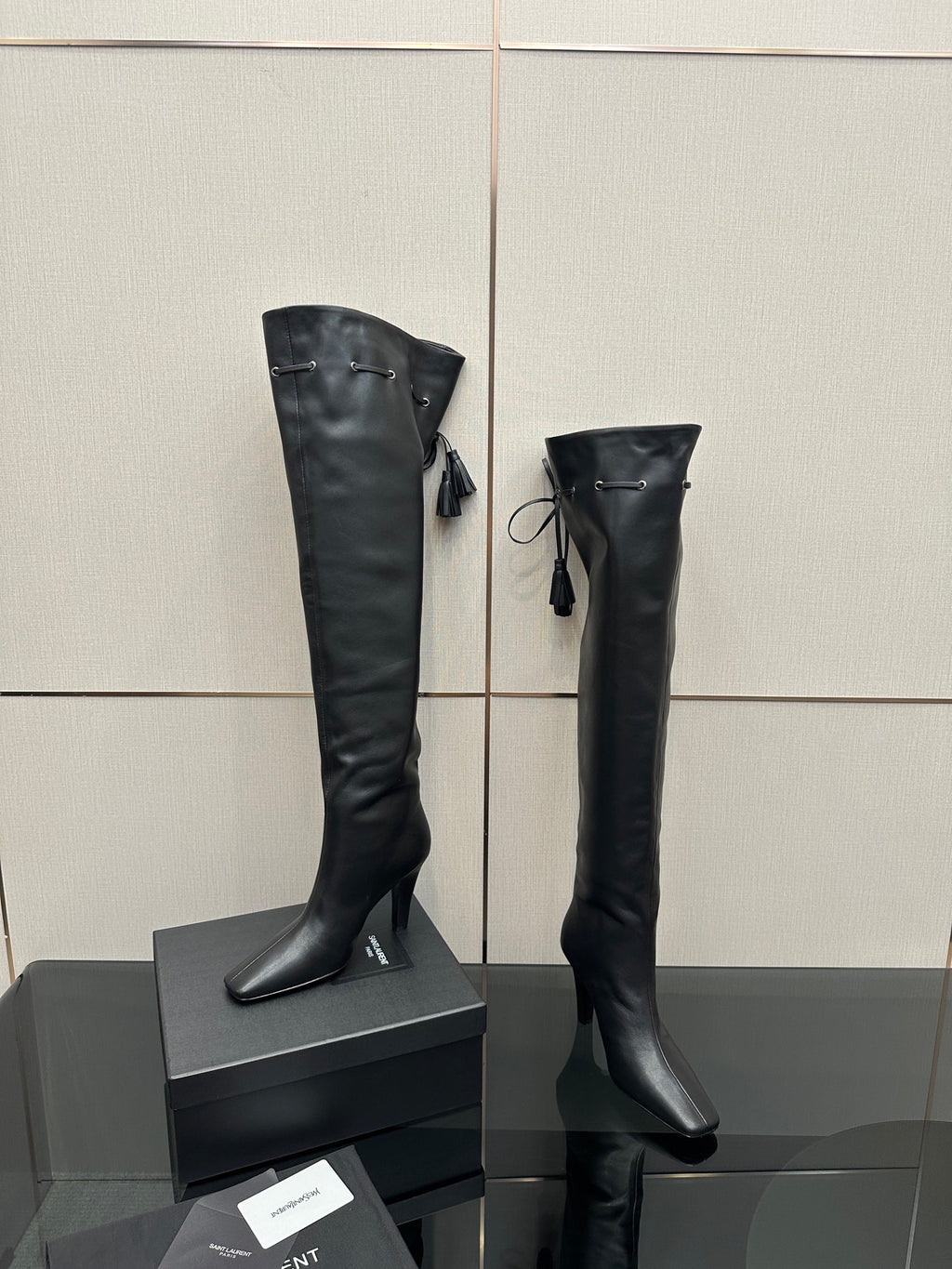 Knee-high black boots with pointed toe, stiletto heel, tie tassel detail