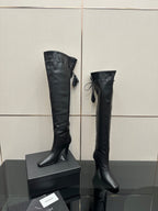 Knee-high black boots with pointed toe, stiletto heel, tie tassel detail