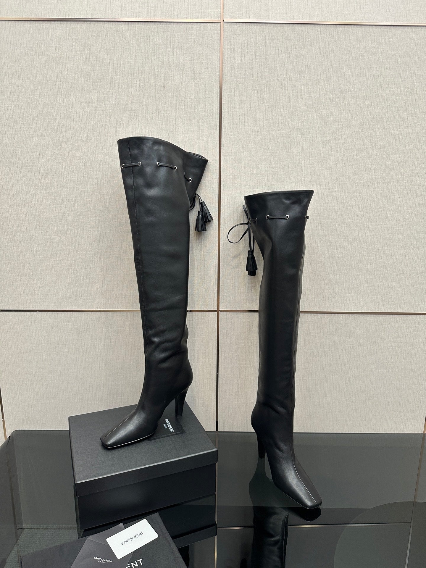 Knee-high black boots with pointed toe, stiletto heel, tie tassel detail
