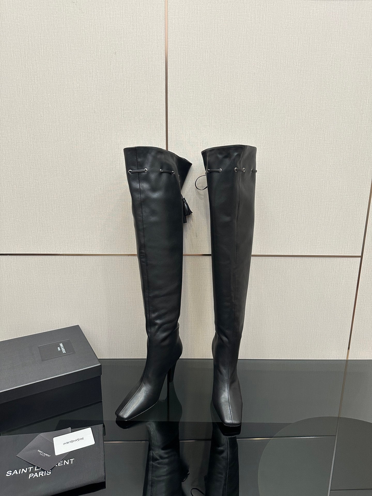 Knee-high black boots with pointed toe and stiletto heel, minimal side strap detail
