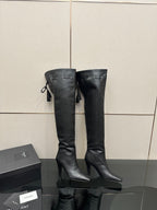 Knee-high black boots with pointed toe, stiletto heel, side tassel detailing