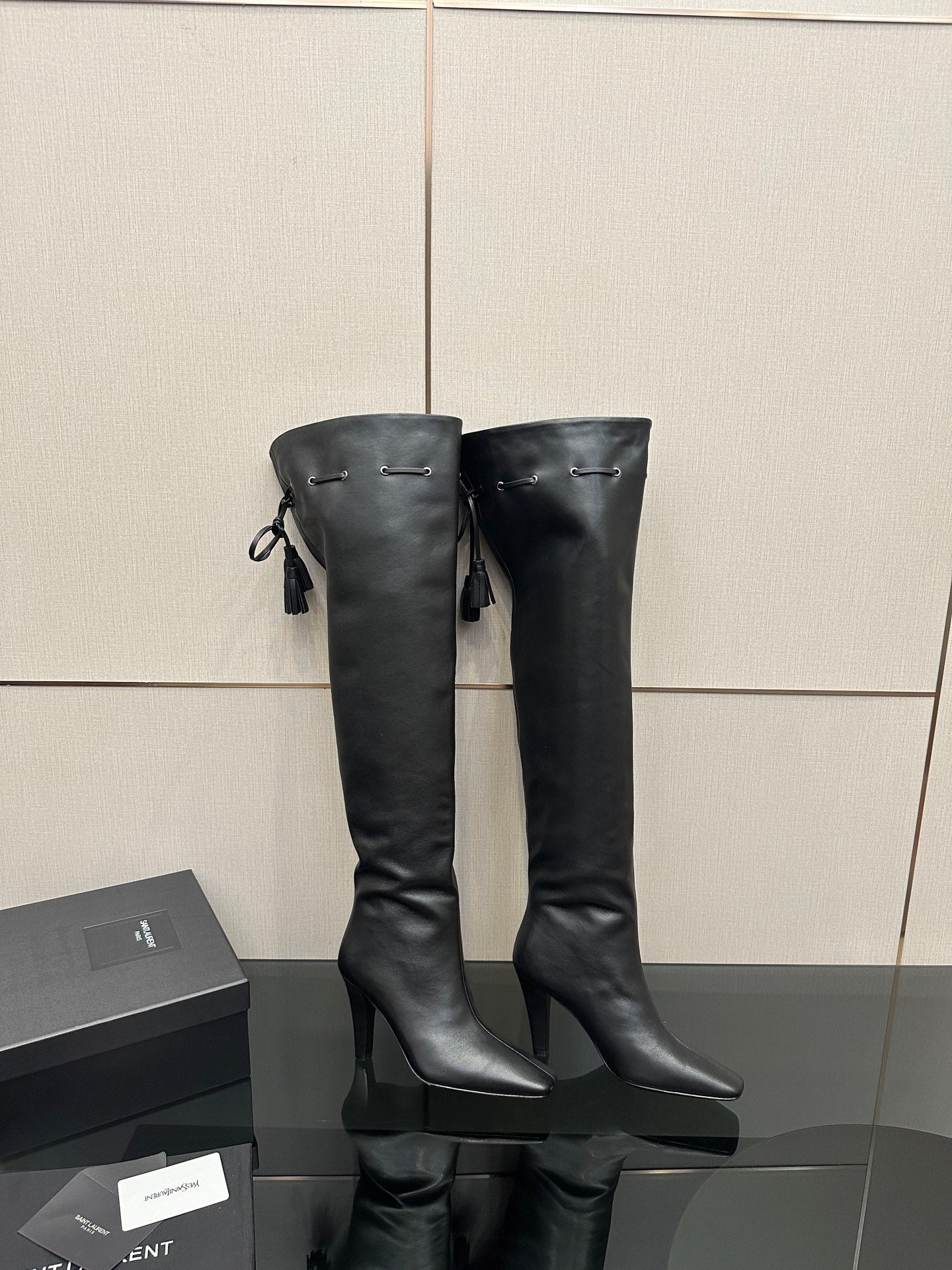 Knee-high black boots with pointed toe, stiletto heel, side tassel detailing