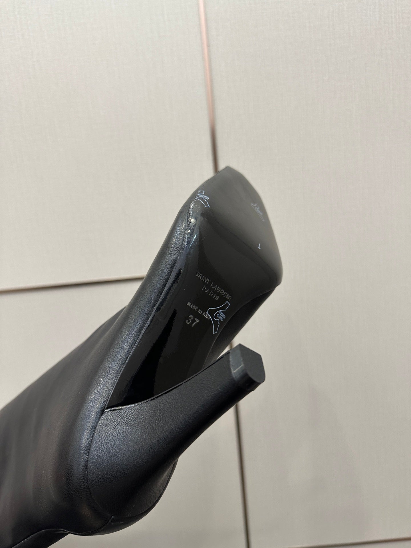 Black knee-high boot close-up with pointed toe, stiletto heel, side tie tassel