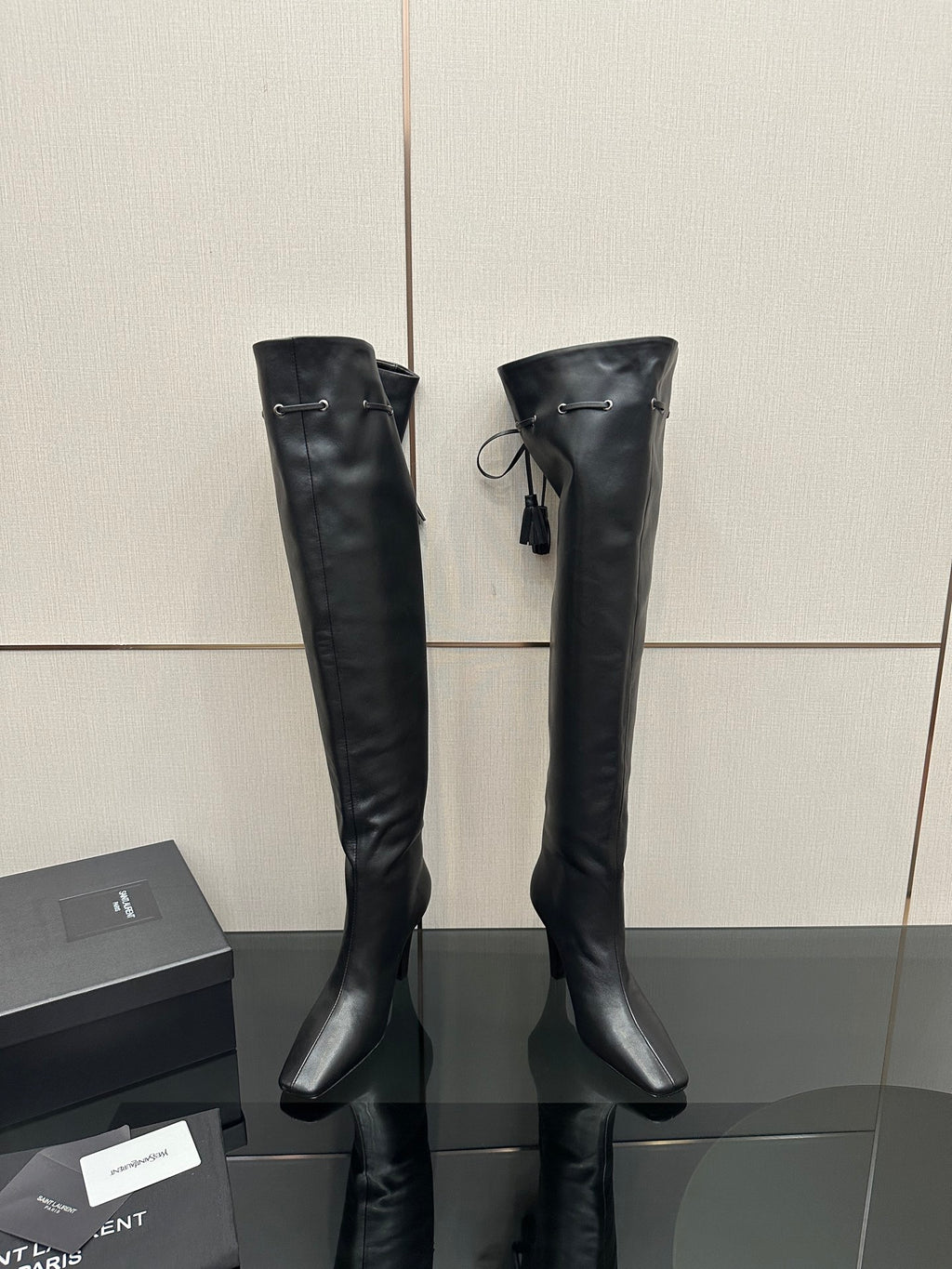 Knee-high black leather-look boots with pointed toe and stiletto heel, front strap detail
