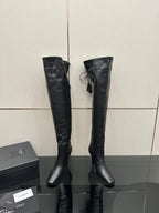 Knee-high black leather-look boots with pointed toe and stiletto heel, front strap detail