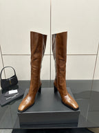 Brown knee-high leather boots with pointed toe and slim heel, paired on display box