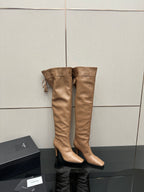 YSL taupe knee-high boots, stiletto heel, tassel tie detail, paired on display