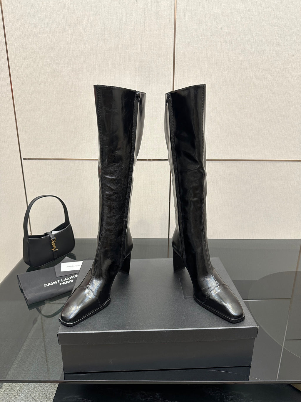 Tall black leather boots with glossy finish, side view of pull-on shaft.