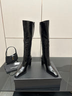 Tall black leather boots with glossy finish, side view of pull-on shaft.