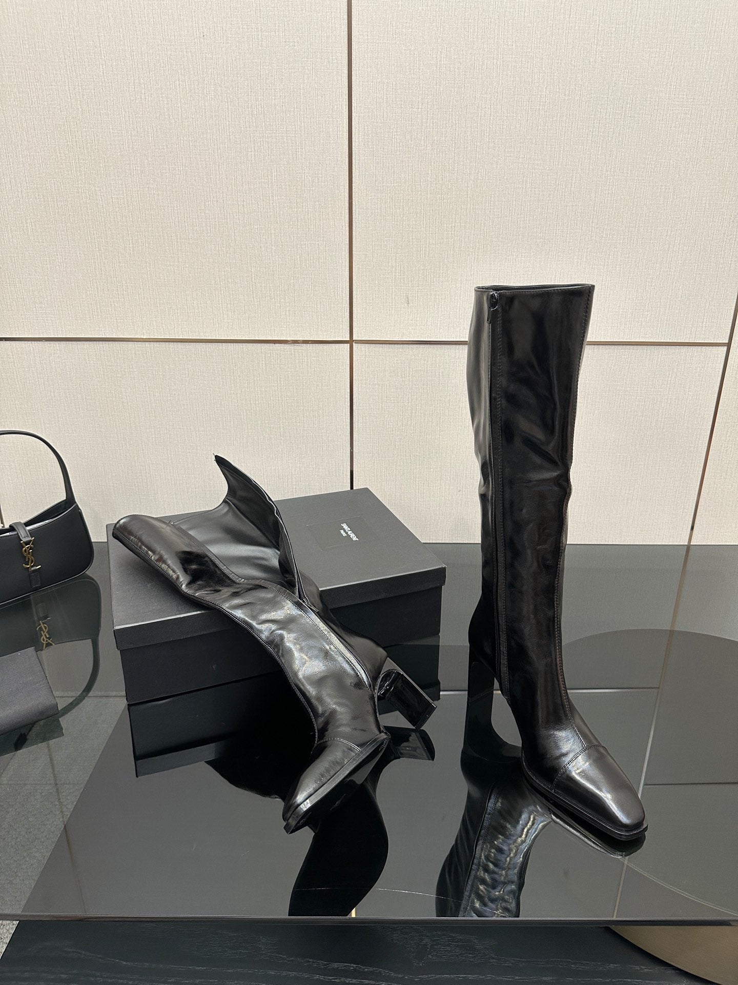 Knee-high black leather boots with pointed toe and slim heel, side view.