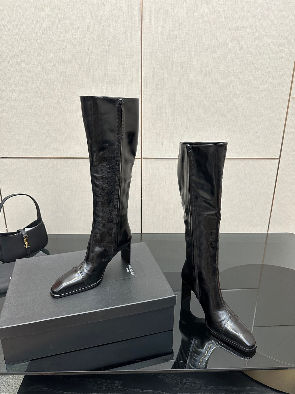 Knee-high black leather boots with slim heel and pointed toe, angled view.