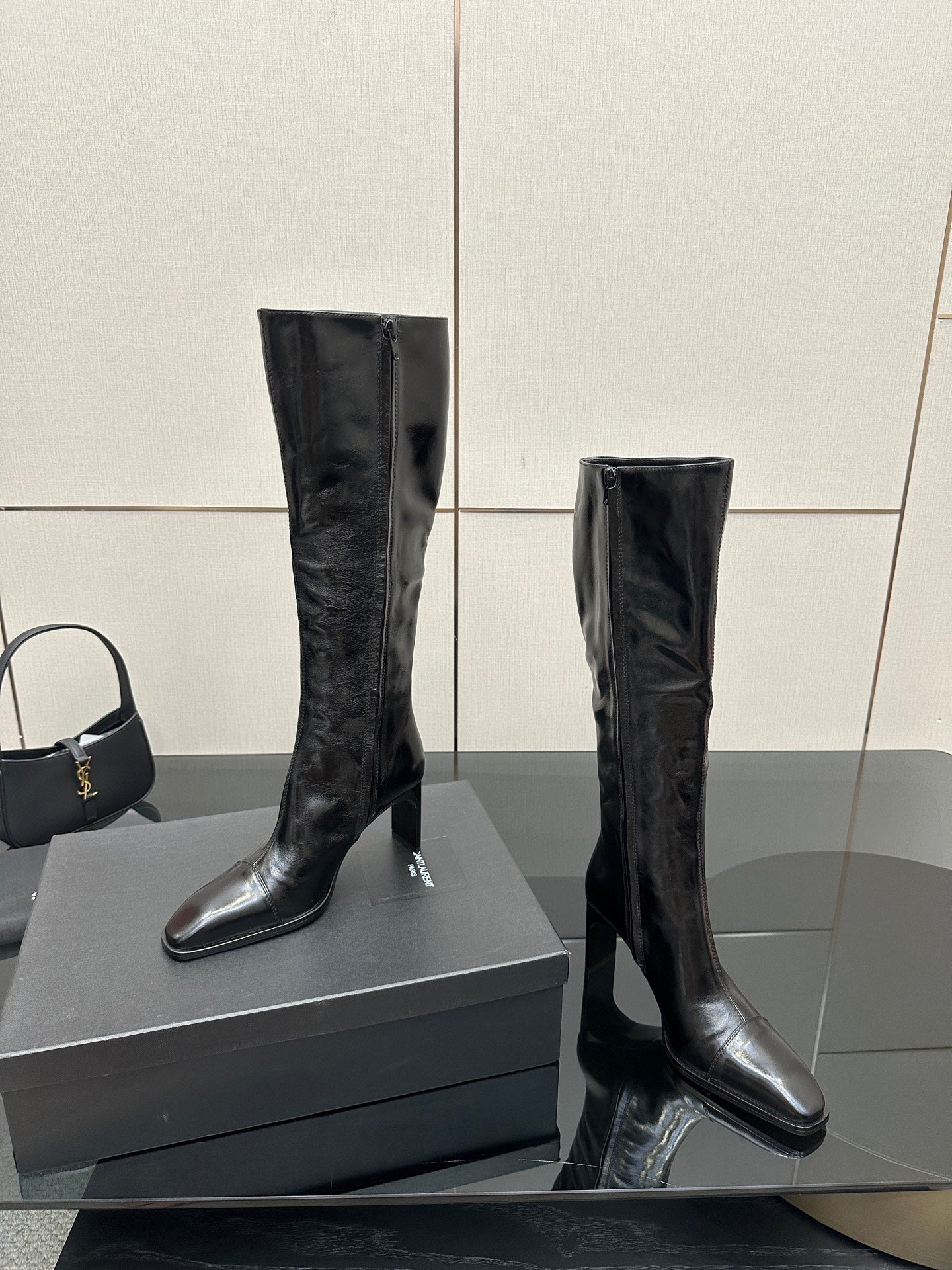 Knee-high black leather boots with slim heel and pointed toe, angled view.