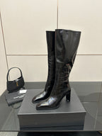 Tall black leather boots with pointed toe and medium heel, side view.