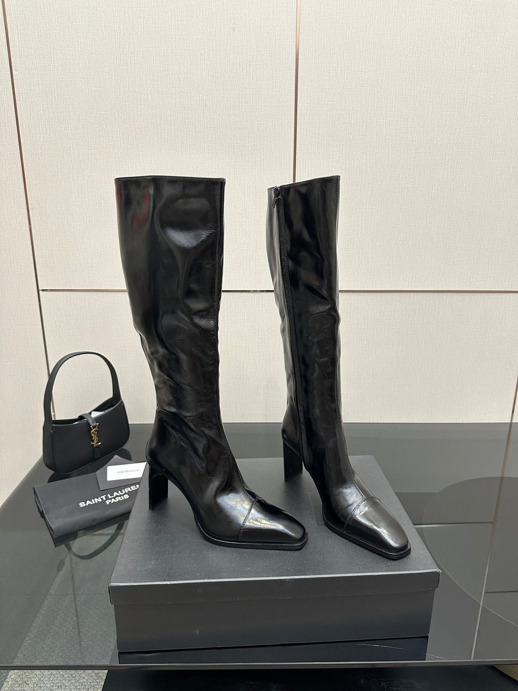 Tall black leather boots with stacked heel and pull-on design, knee-high length.