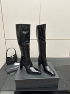 Tall black leather boots with stacked heel and pull-on design, knee-high length.
