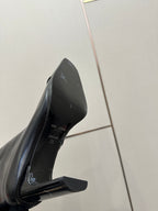 Black leather tall boot close-up, insole logo and block heel visible.