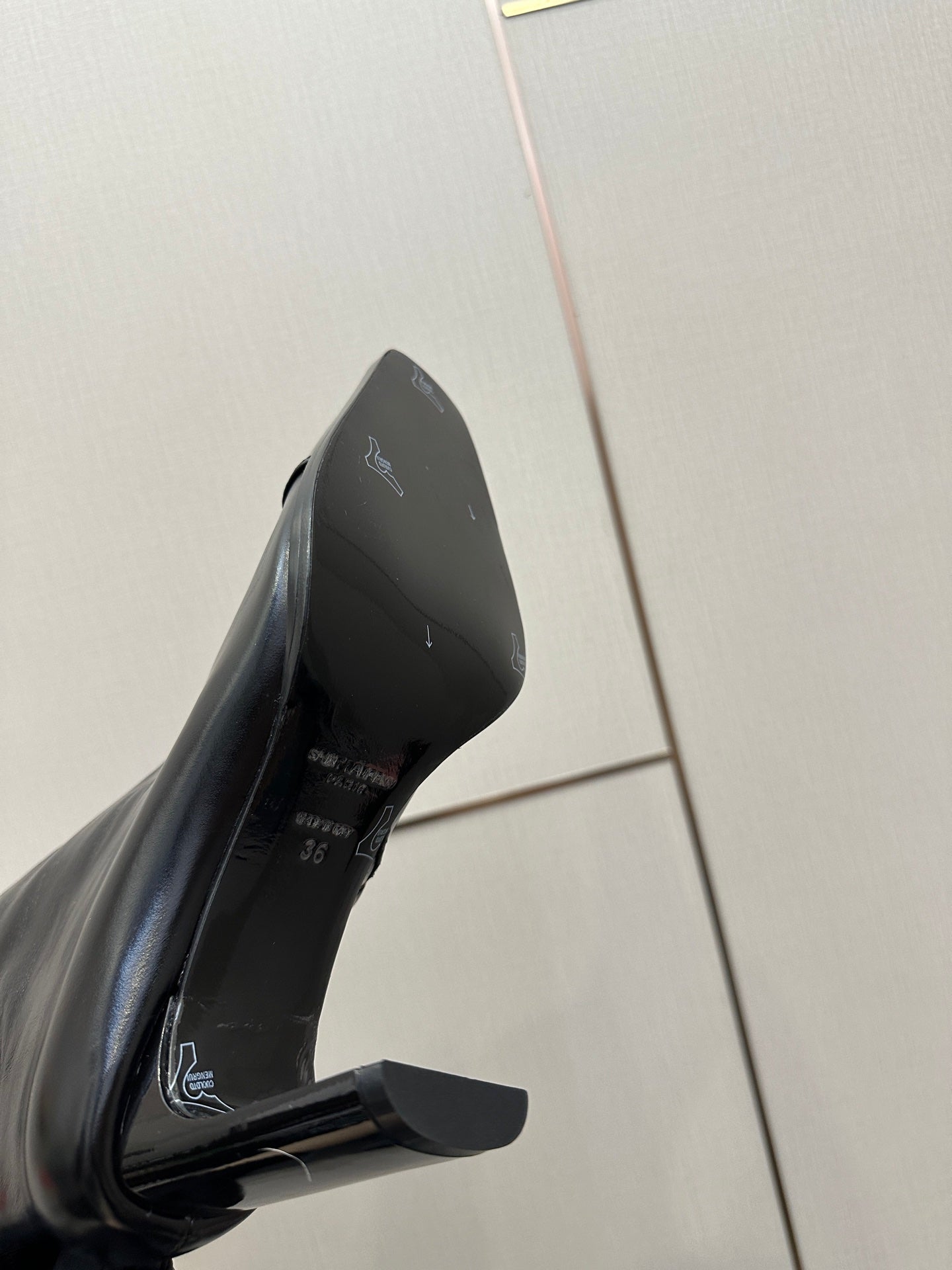 Black leather tall boot close-up, insole logo and block heel visible.