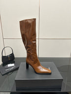 Brown knee-high leather boots with pointed toe and slim heel, single boot on display box