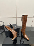 Brown knee-high leather boots with pointed toe and slim heel, one boot on its side