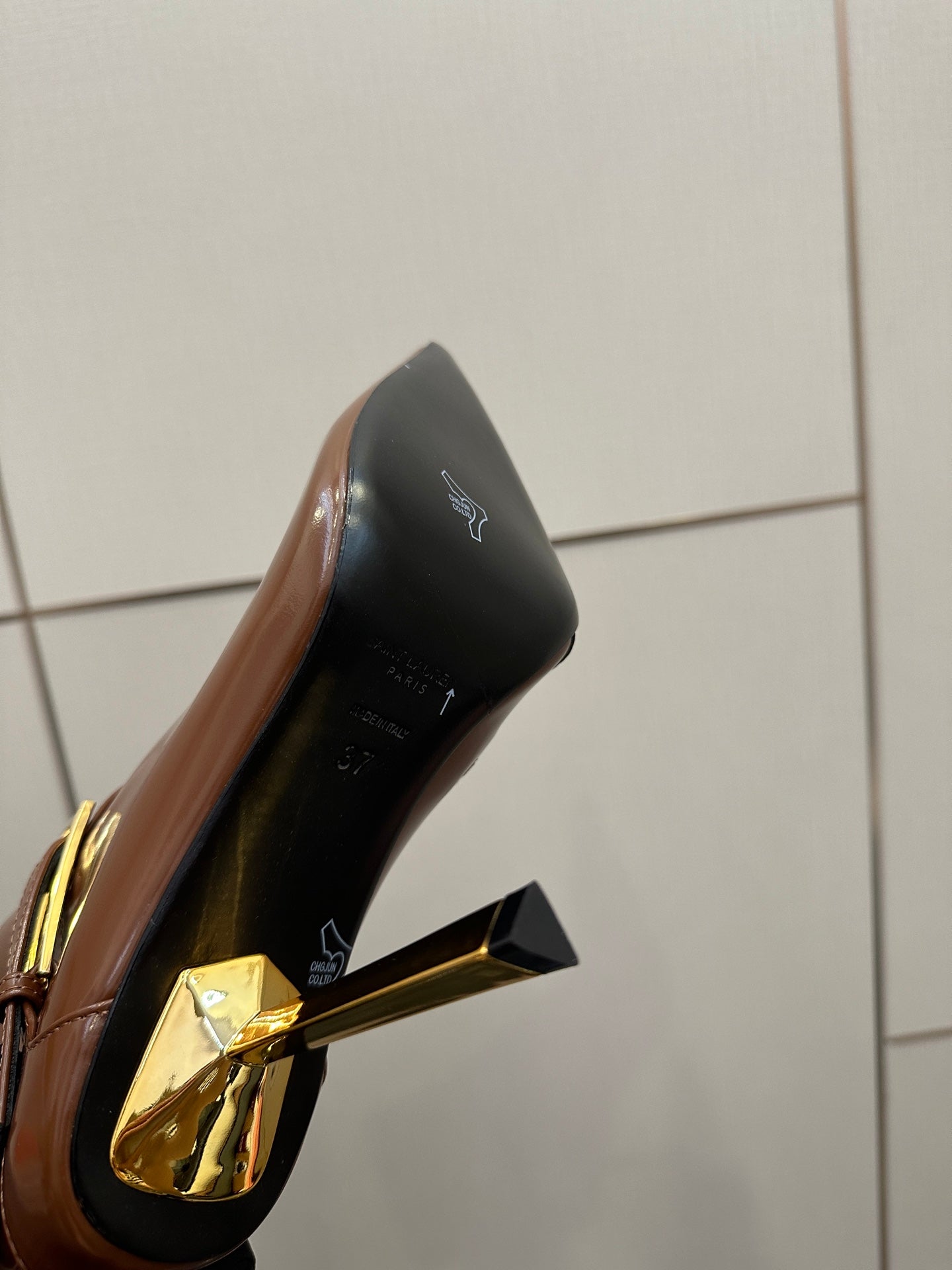 Women’s tan leather ankle boot close-up, black heel panel with gold accent