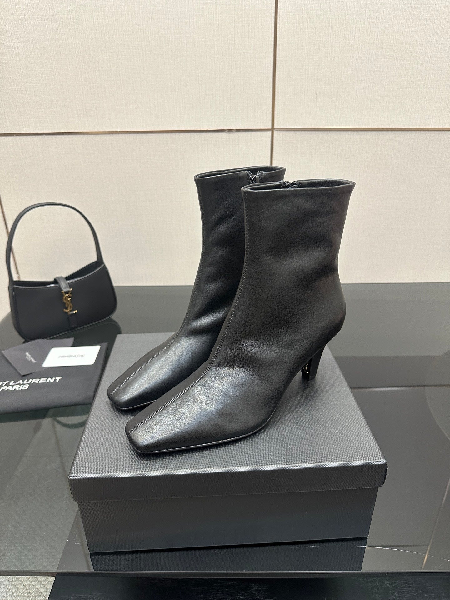Black heeled ankle boots with pointed toe on a display box