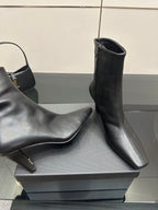 Close view of black ankle boots with block heels on a display box