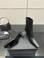 Black ankle boots with block heels on a display box