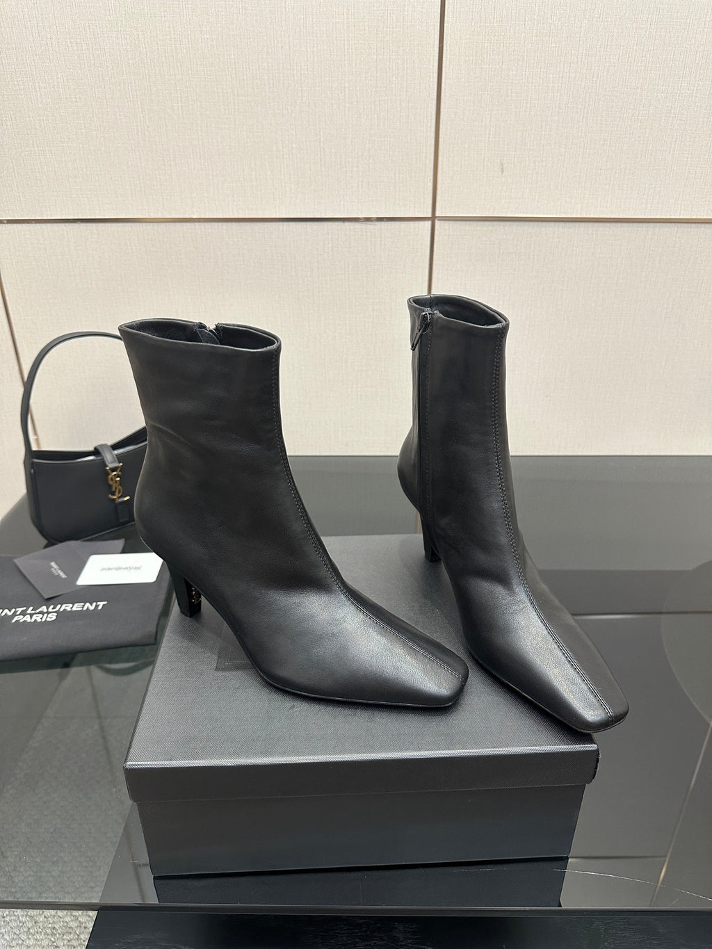 Two black ankle boots with block heels on a display box