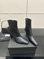 Two black ankle boots with block heels on a display box