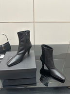Black ankle boots with block heels on a display box, side view
