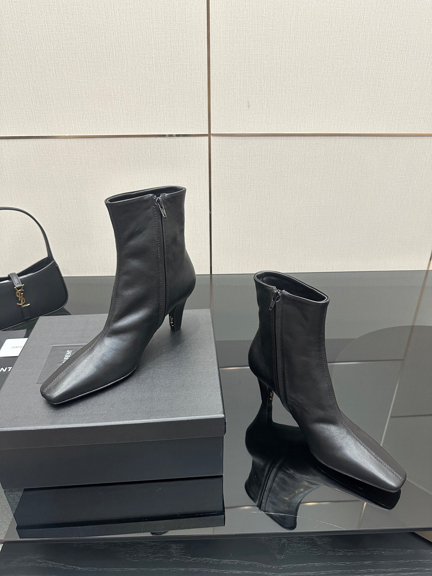 Black ankle boots with block heels on a display box, side view