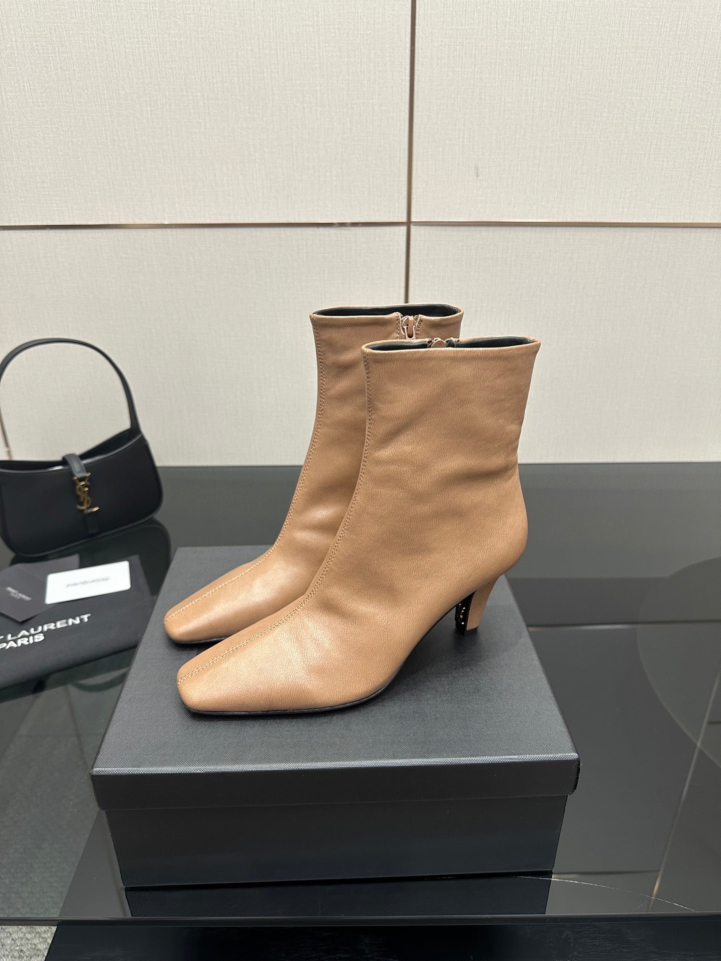 Beige ankle boots with pointed toe and slim high heel, side view on box
