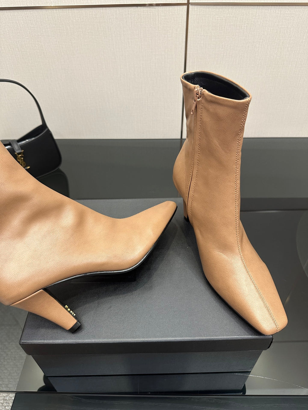 Beige pointed-toe ankle boots with slim heel, front and side angles on box
