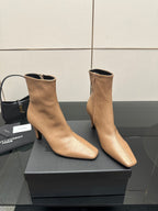 Beige pointed-toe ankle boots with slim high heel, angled pair on box