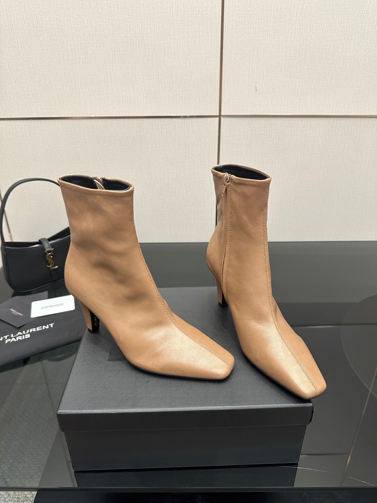 Beige pointed-toe ankle boots with slim high heel, angled pair on box