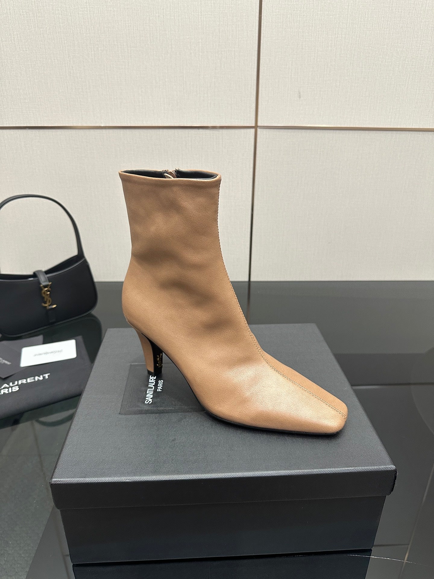 Beige pointed-toe ankle boot with slim heel, side view on black box