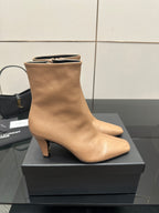 Beige ankle boot with pointed toe and slim high heel, close side view on box