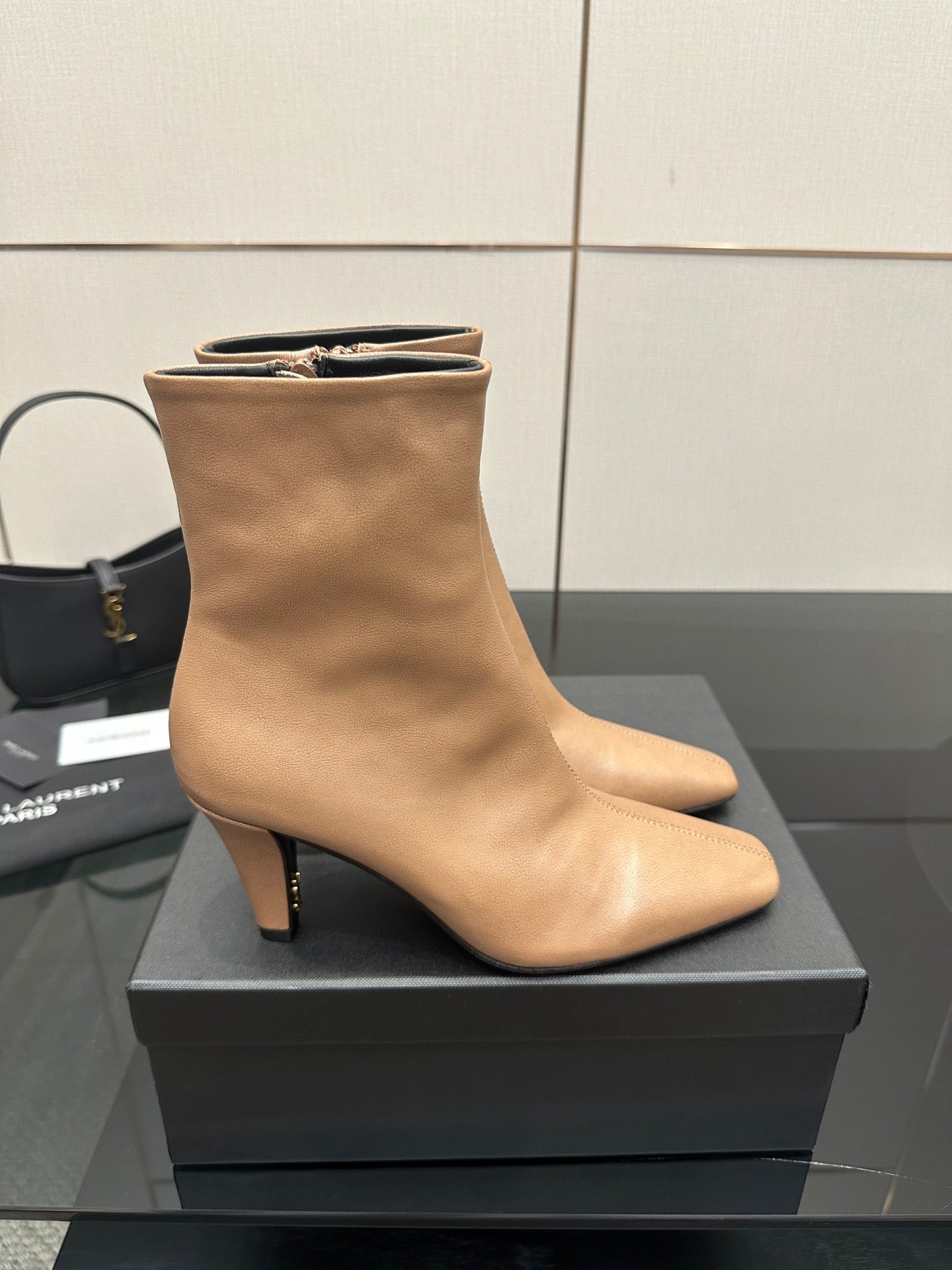 Beige ankle boot with pointed toe and slim high heel, close side view on box