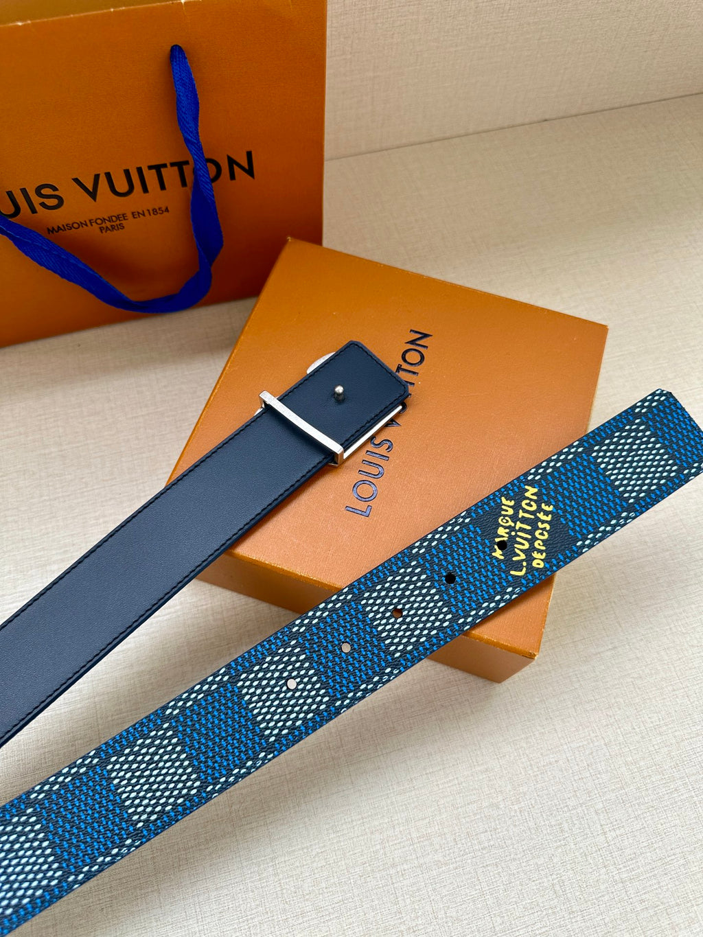 Blue Louis Vuitton belt with rectangular pin buckle and LV logo buckle detail.