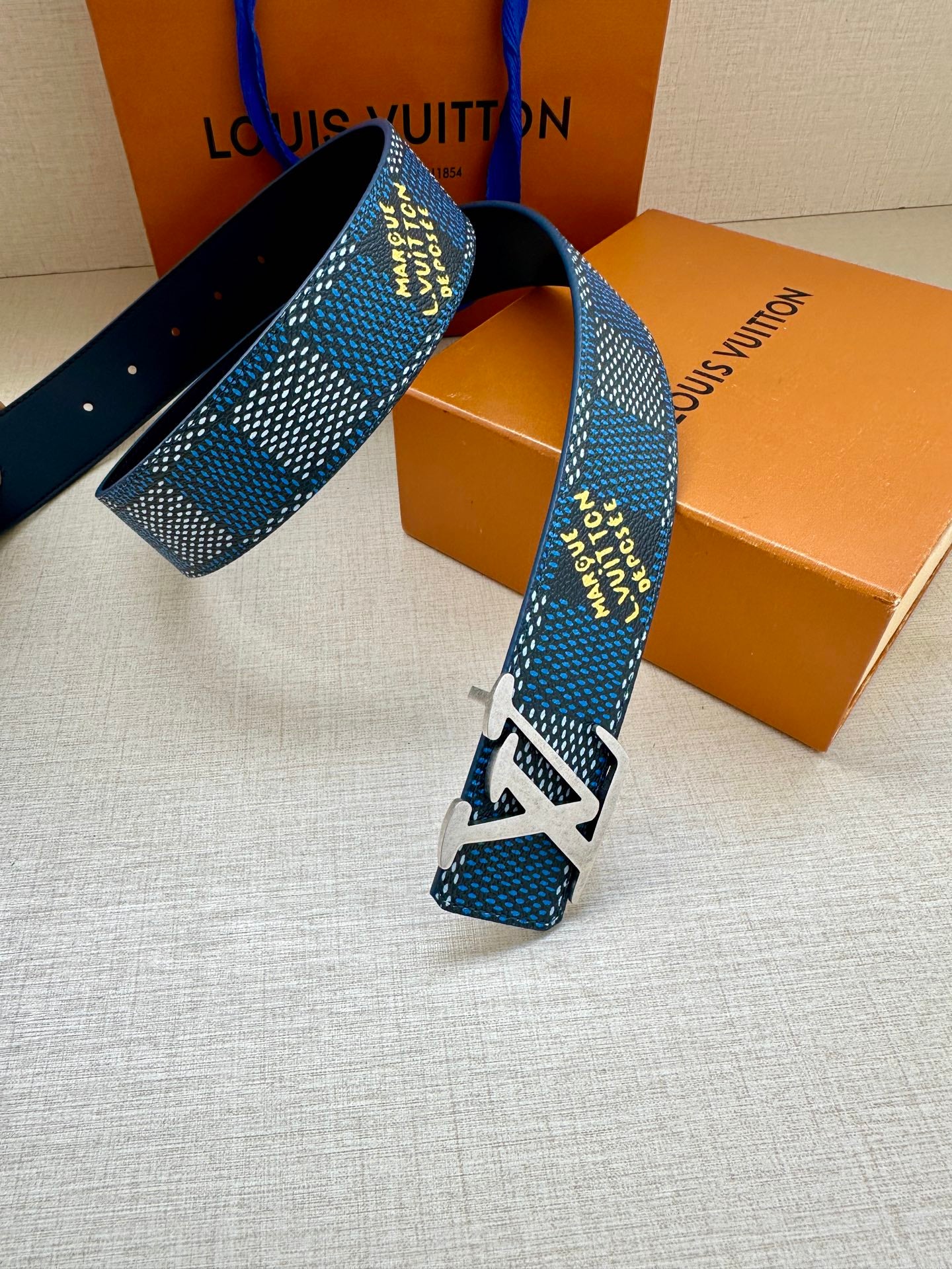 Blue Louis Vuitton belt draped with LV logo buckle and studded leather strap holes.