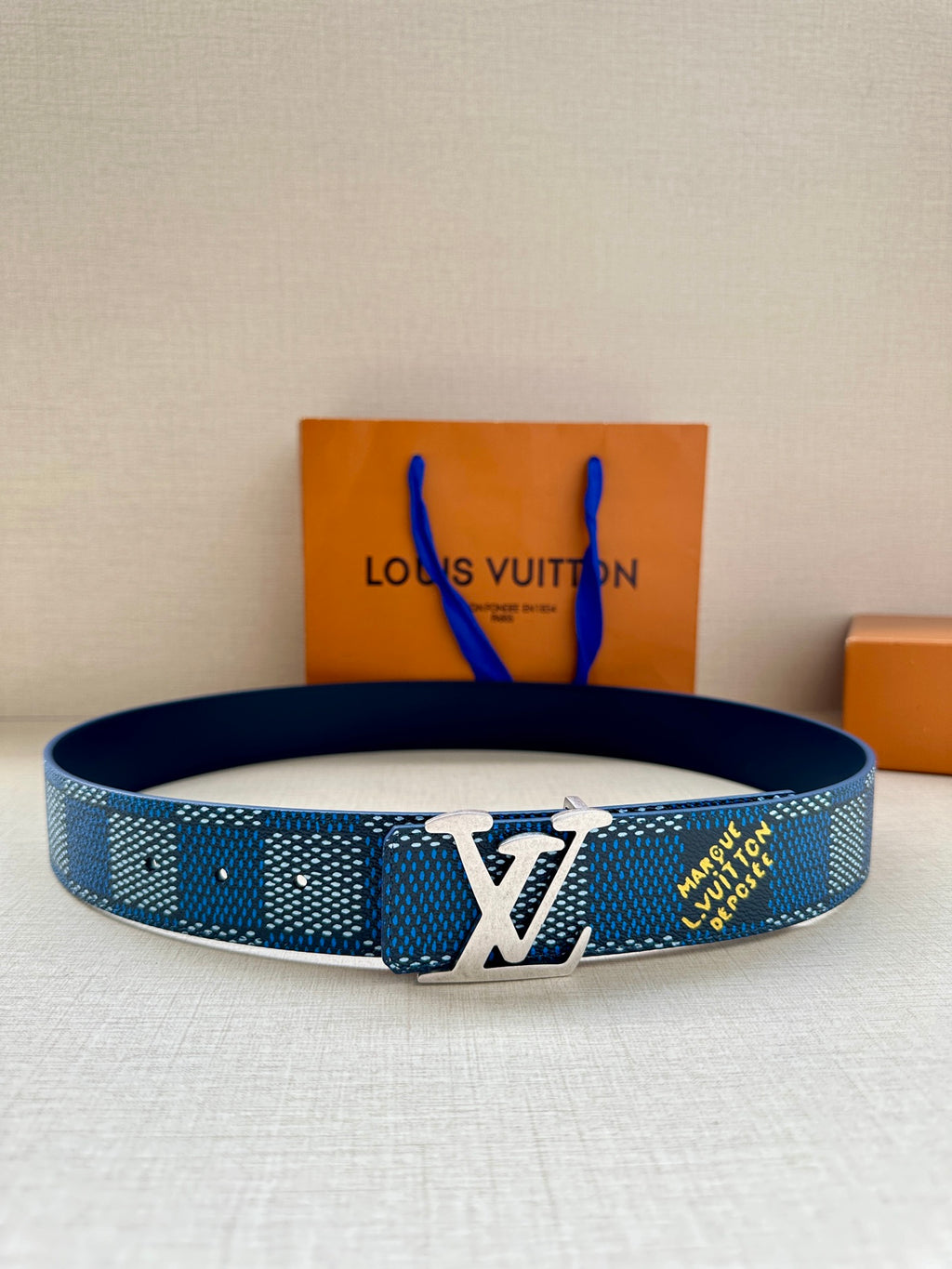 Blue Louis Vuitton belt with LV logo buckle and perforated strap holes.
