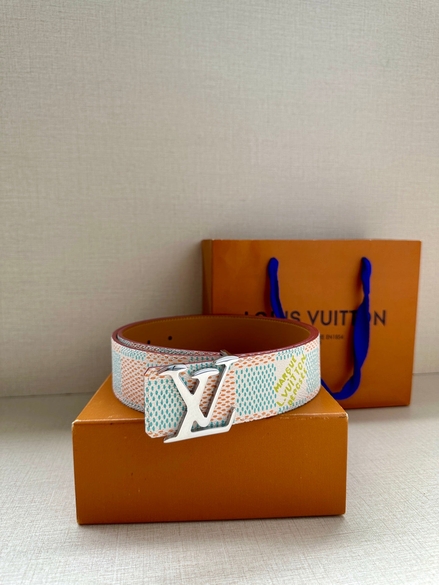 Louis Vuitton belt with pastel blue patterned strap and silver-toned buckle on box.
