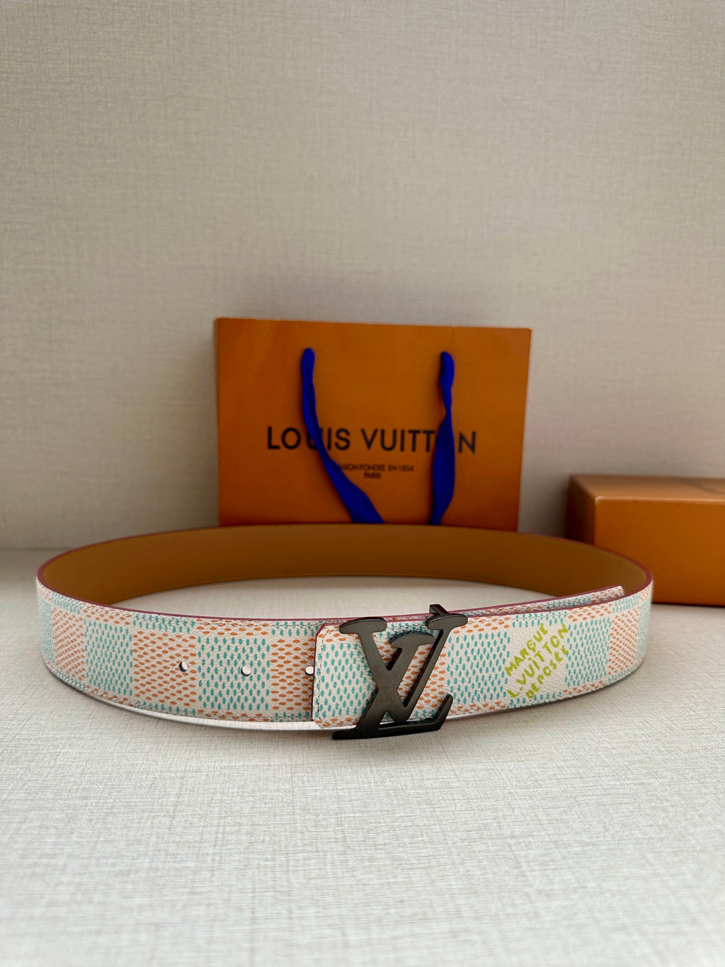 Louis Vuitton belt with pastel blue patterned strap and black LV buckle.